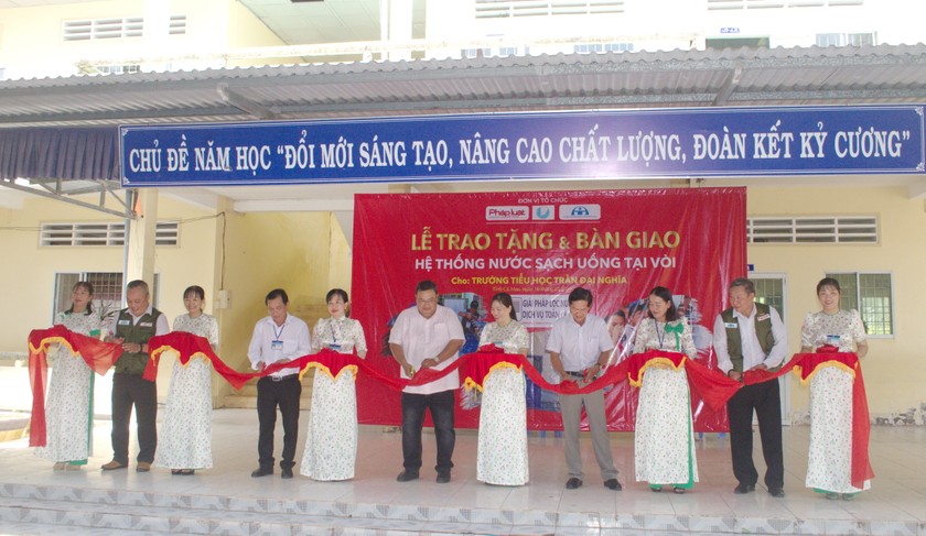 Các đại biểu thực hiện nghi thức cắt băng khánh thành Hệ thống lọc nước lọc cho Trường Tiểu học Trần Đại Nghĩa (xã Khánh Tiến, huyện U Minh).