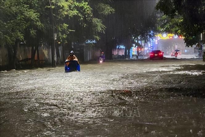 Người và phương tiện giao thông di chuyển khó khăn trên đoạn đường ngập sâu ở thành phố Điện Biên Phủ. Ảnh: Thông tấn xã Việt Nam