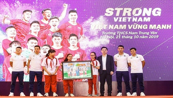 Các cầu thủ CLB bóng đá Hà Nội và Trưởng Ban tổ chức chương trình “Strong Vietnam” Đỗ Vinh Quang nhận quà là bức tranh từ các em học sinh THCS Nam Trung Yên
