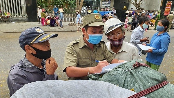 Người dân nhờ cán bộ dân phố điền thông tin vào phiếu hẹn phát gạo.