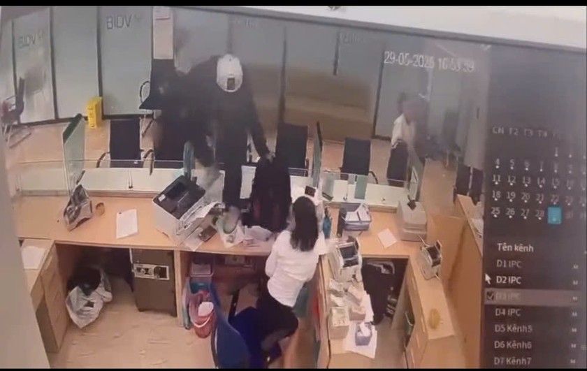 Sau khi đe dọa nhân viên ngân hàng, tên cướp trèo qua vách ngăn tiến sâu vào trong quầy giao dịch (Ảnh cắt từ clip)